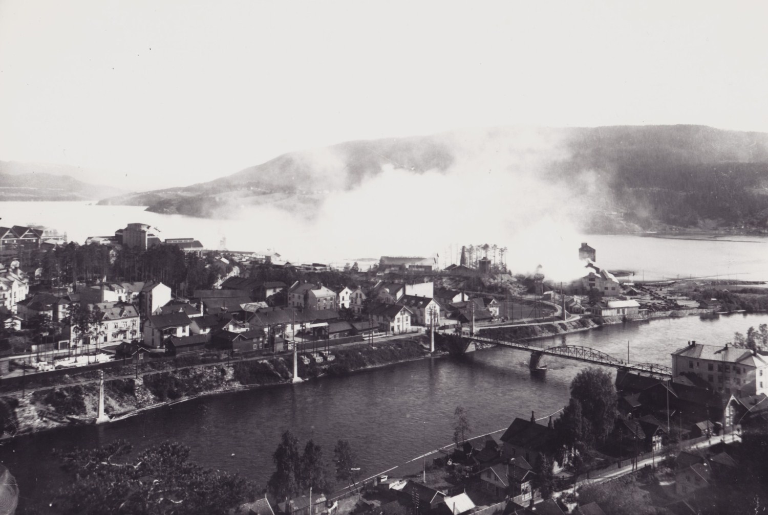 1 - <p><strong>Oversiktsbilde over den nedre delen av Notodden by ca.1915.</strong> Bildet er tatt fra Ramsflog og ned mot nedre delen av byen. Tinfos Jernverk er med på bildet, det kom i 1912.</p>